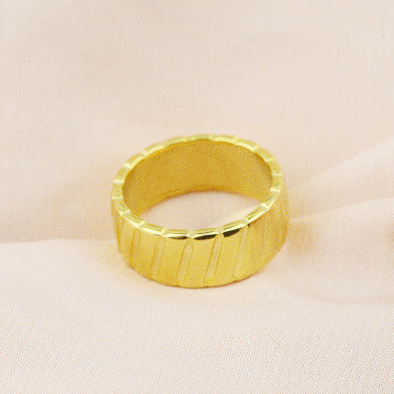Bague en acier titane avec motif biseauté en or 18 carats, élégante et moderne, portée sur le doigt.