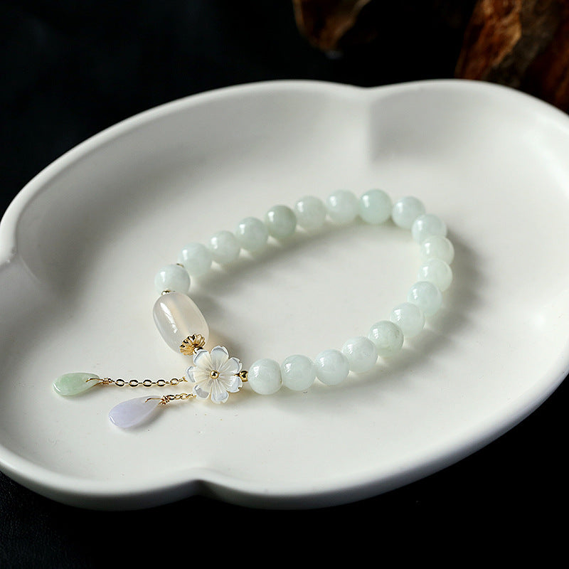 Bracelet en jade naturel avec motif de fleur en or 14 carats, bijou élégant et artisanal.