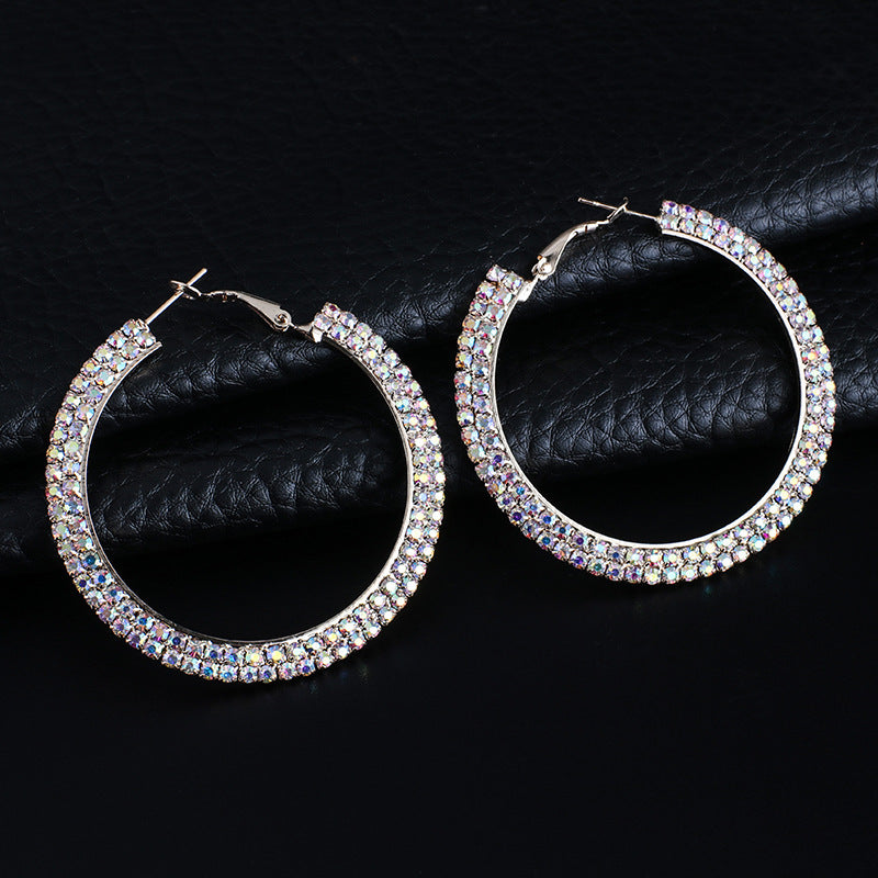 Boucles d'oreilles rondes en cristal de luxe pour femmes, accessoires élégants de la marque Aura Scent, visibles en image.