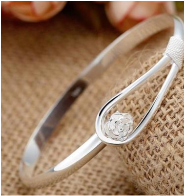 Bracelet en argent plaqué or avec motifs de fleurs de cerisier, délicat et élégant, porté sur un poignet.